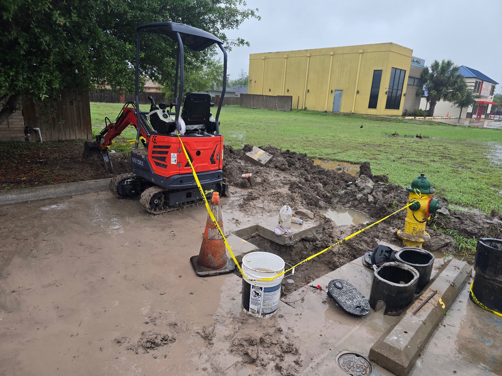 Mini excavator on demolition jobsite with broken concrete and exposed utilities