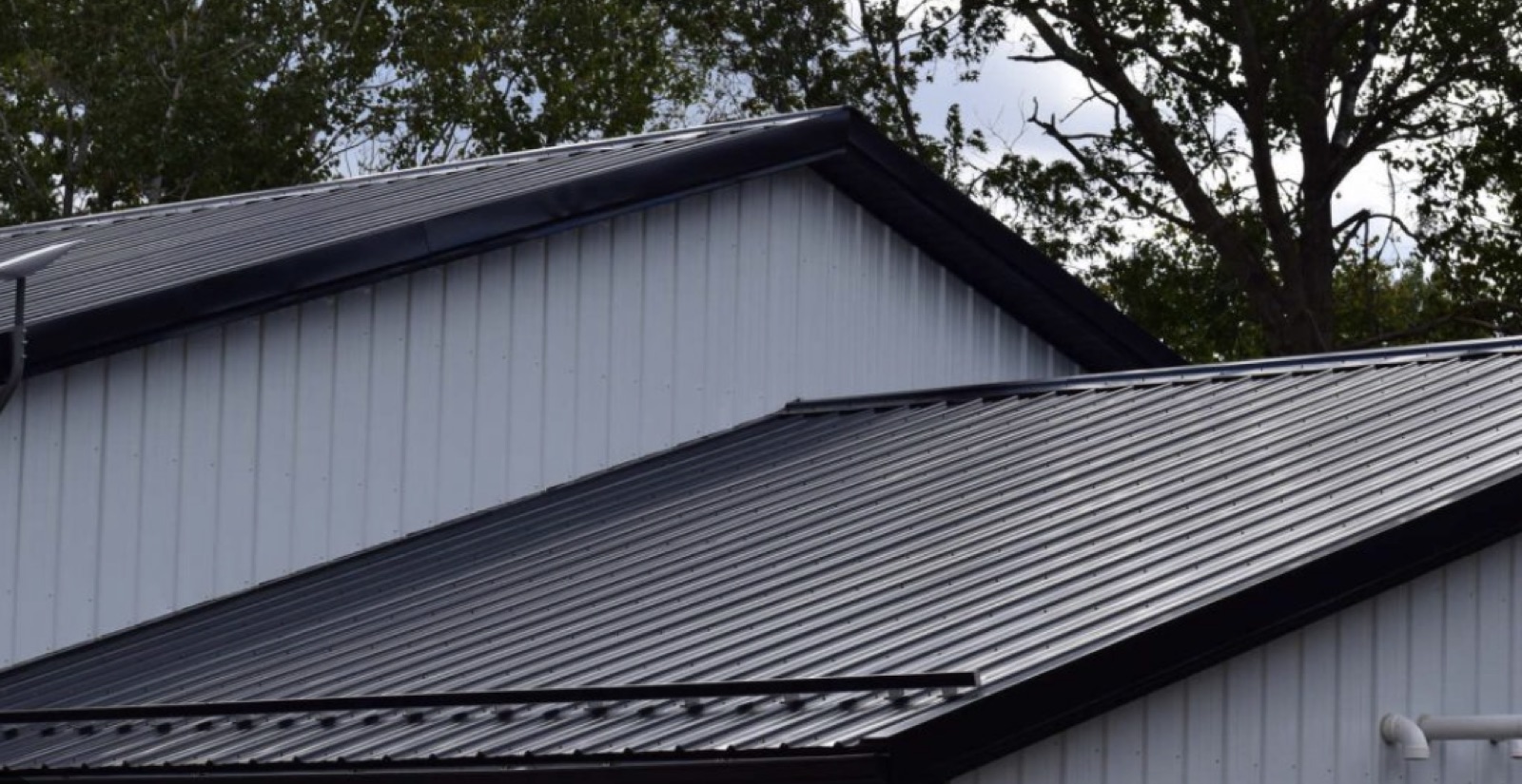 Charcoal standing-seam metal roof at hip ridge, residential build