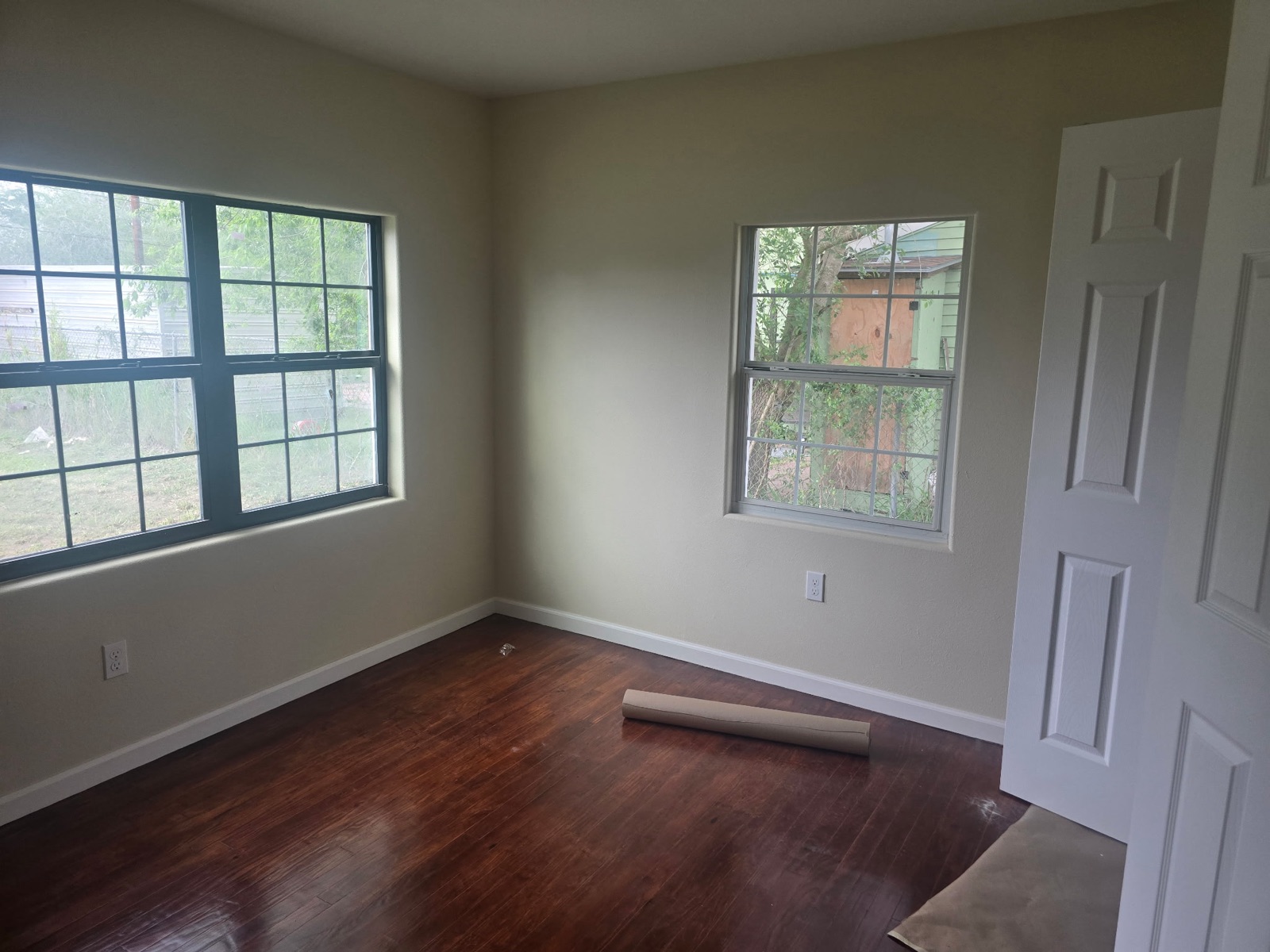 Refreshed interior room with refinished dark hardwood and double-hung windows
